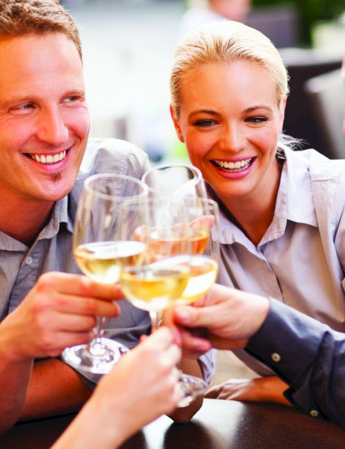 A smiling group of friends cheers with champagne glasses at a restaurant, sharing a fun moment together.