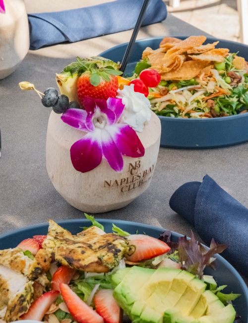 A salad bowl with greens, strawberries, radish, and chips, paired with chopsticks and a colorful flower garnish beside it.